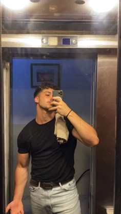 a man taking a selfie in front of a mirror with his hand on his hip