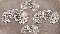 three pieces of fabric with white embroidery on them