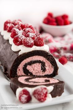 a piece of chocolate cake with raspberries on top and a roll in the middle