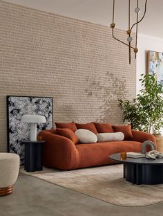 a living room filled with furniture next to a tall brick wall and potted plant