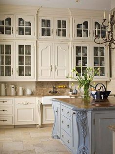 a large kitchen with white cabinets and marble counter tops, an island in the middle