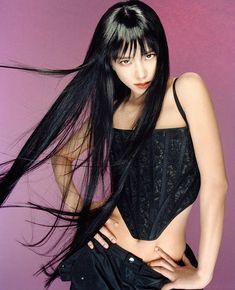 a woman with long black hair posing for the camera