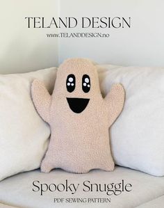 a stuffed ghost sitting on top of a white pillow with the words spooky snuggle