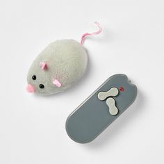 a stuffed animal next to a remote control on a white surface with a pink ribbon