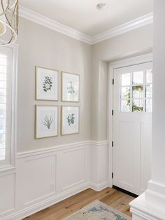 a white room with four framed pictures on the wall and a rug in front of it