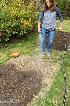 a woman is watering her yard with a hose