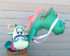 an inflatable dragon head sitting on top of a barrel next to a stuffed animal