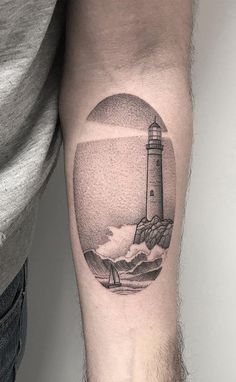 a man's arm with a lighthouse tattoo on it