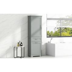 a bathroom with a white bathtub and sink next to a tall cabinet in front of a window