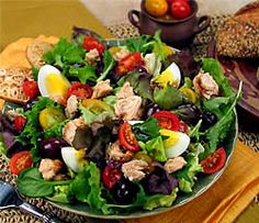 a salad with hard boiled eggs, tomatoes, olives and lettuce in it