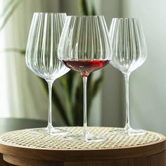 three wine glasses sitting on top of a wooden table