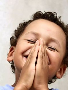 a young boy covers his mouth with his hands