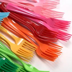 there are many different colored plastic forks lined up on the table with one fork in the middle