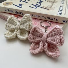 two crocheted butterfly keychains sitting on top of a book