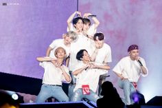 group of young men standing on stage with one holding up his arms in the air