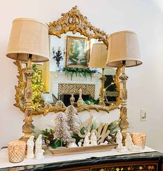 a table with two lamps on it and a mirror in the corner above it that is decorated for christmas