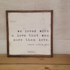 a wooden frame with a quote on it sitting on top of a wood shelf next to a white wall