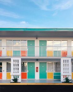 an apartment building with multicolored doors and balconies on the second floor