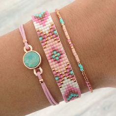 three different bracelets with beads and stones on the wrist, one has a round bead