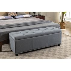 a large bed with a gray upholstered foot board and storage bench underneath it