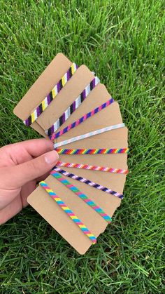 a hand holding several paper straws on top of green grass