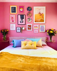 a bedroom with pink walls, yellow bedding and pictures on the wall above it