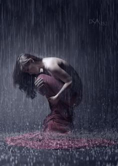 a woman kneeling down in the rain with her head on her hands and eyes closed