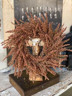 a vase filled with pink flowers sitting on top of a wooden table next to an old photo