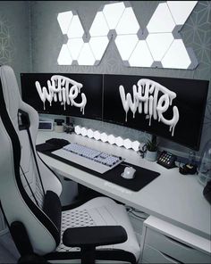 a computer desk with two monitors and a keyboard on it, covered in white graffiti