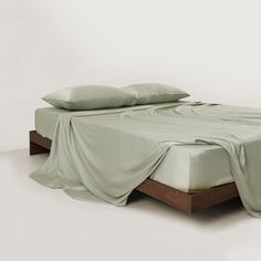 an unmade bed with two pillows on top of it and a sheet draped over the headboard