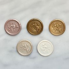 four different types of buttons on a marble surface with white and gold trimmings