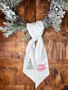 a white scarf with a christmas tree on it sitting on top of a wooden floor