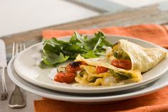 a white plate topped with an omelet and vegetables