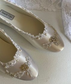 a pair of white shoes with beaded details on the toes and heel are sitting next to a lace doily