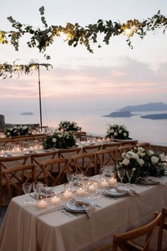 an outdoor dining area with tables and chairs set up for a formal dinner overlooking the ocean