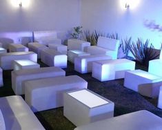 a room filled with lots of white couches and tables covered in light up cubes