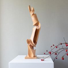 a wooden sculpture sitting on top of a white block