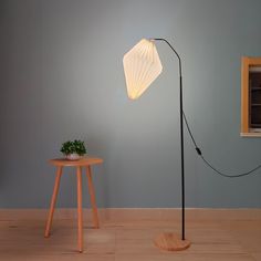 the floor lamp is next to a small table with a potted plant on it