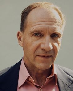 a man in a suit and pink shirt looking at the camera with an intense look on his face