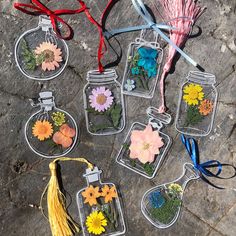 several glass jars with flowers in them sitting on the ground next to some tassels