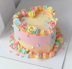 a cake decorated with flowers and icing on top of a white table next to confetti