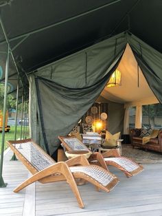 two lawn chairs sitting under a tent on top of a wooden deck