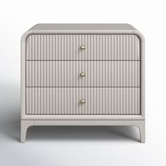 a white dresser with three drawers and two handles on it's sides, against a gray background