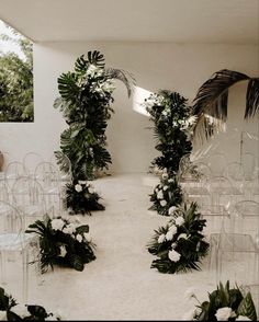 a room filled with lots of clear chairs covered in flowers and greenery next to a wall