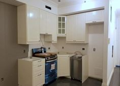 an empty kitchen with white cabinets and appliances