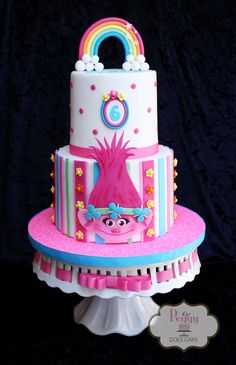 a pink and blue cake on top of a white stand with a rainbow in the middle