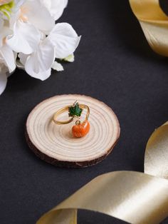 an orange ring sitting on top of a piece of wood next to some white flowers