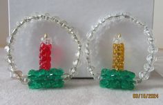 two small candles are sitting in the middle of a pair of glass bead hoop earrings