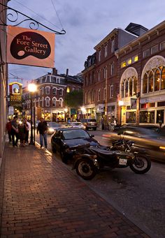 a motorcycle parked on the side of a street next to a car and some people