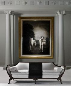 two white dogs are standing in front of a black and white painting on the wall